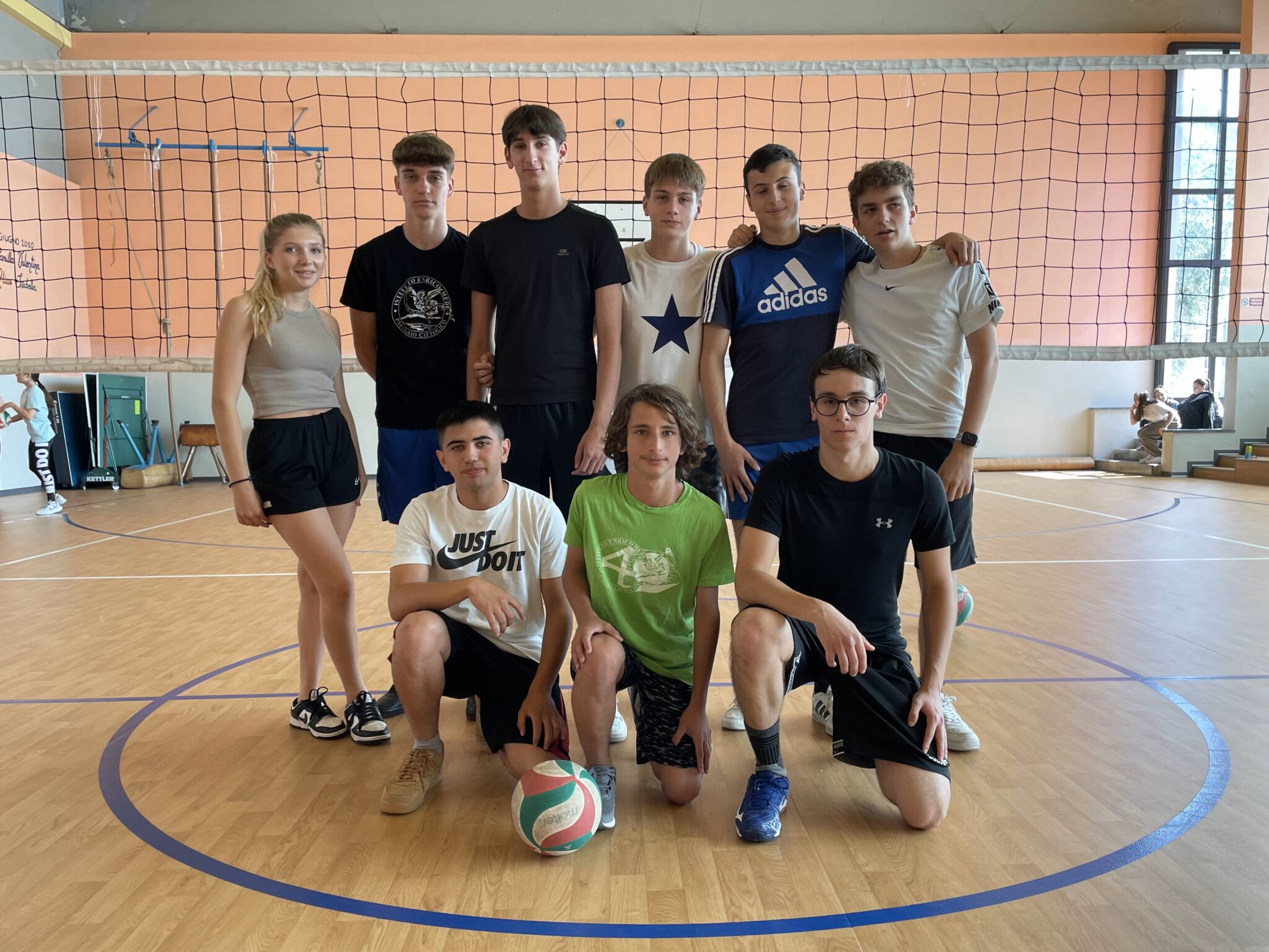 ragazzi in gruppo in palestra con rete pallavolo
