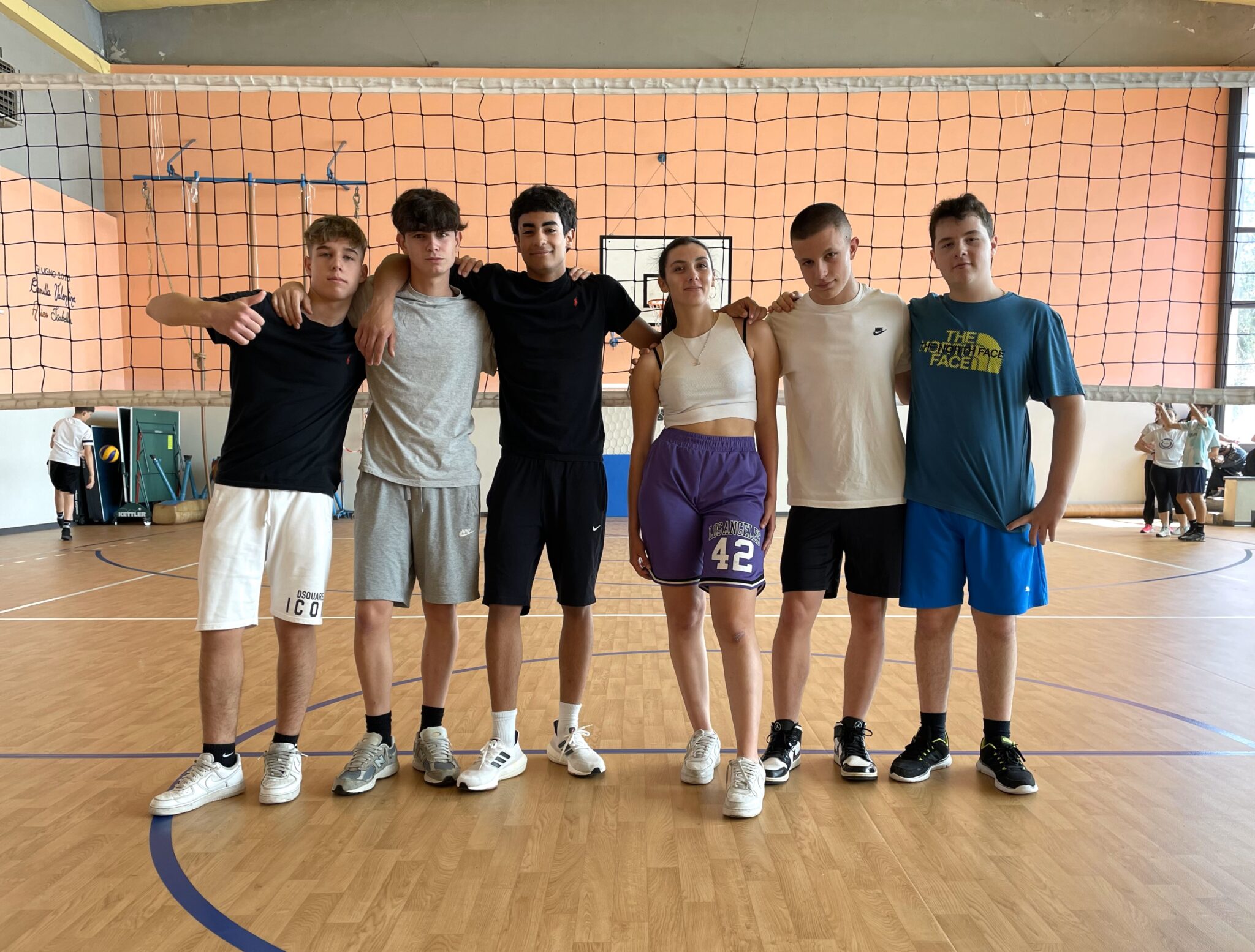 ragazzi in gruppo in palestra con rete pallavolo